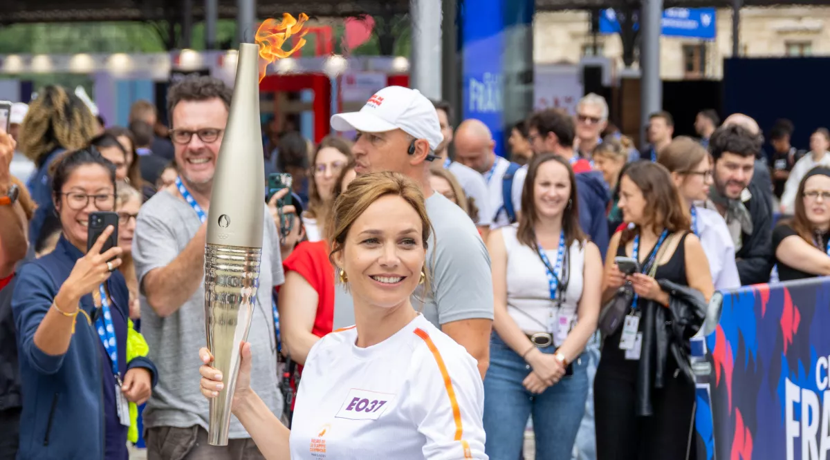 Nathalie Péchalat portant la flamme devant le Club France. 